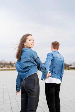 Happy young loving couple embracing each other outdoors in the park having fun holding red balloons