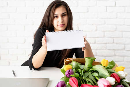 Small business concept. woman hands working on digital tablet, bucket of fresh tulips on background