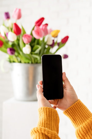 Beautiful young brunette woman in yellow sweater with bouquet of fresh pink tulips and blank calendar for mock upの写真素材