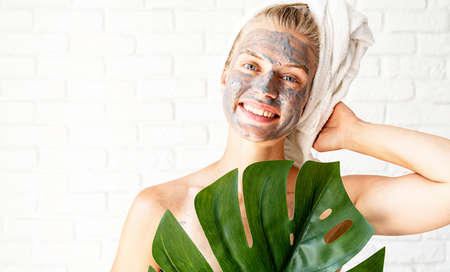 Happy laughing young woman in white bath towels doing morning make up applying face cream looking at...
