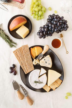 Cheese plate assortment served with honey, grapes, bread and rosemaryの写真素材