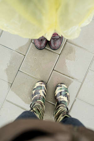 Top view of two pairs of female feet standing in puddles in rainy dayの写真素材