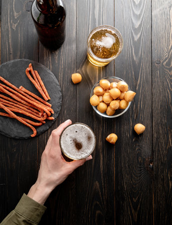 Top view of woman hands holding glass of beer, black wooden backgroundの写真素材