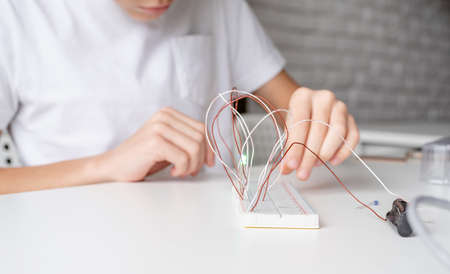 boy hands working with LED lights on experimental board for science projectの写真素材