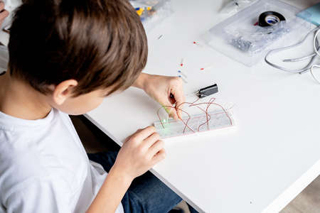 boy hands working with LED lights on experimental board for science projectの写真素材