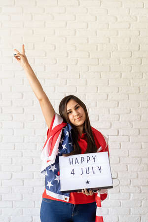 Independence day of the USA. Happy July 4th. Woman with american flag holding lightbox with words...