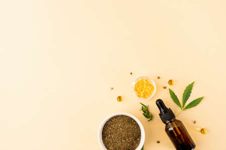 Alternative medicine, natural cosmetics. cbd oil and cannabis leaves cosmetics top view on orange background, flat layの写真素材