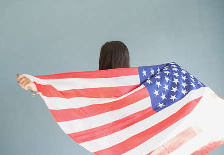 beautiful young woman with american flag on blue backgroundの写真素材