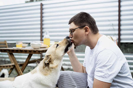 Caucasian man kissing a dog, walking outdoors in the backyardの写真素材
