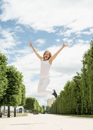 Happy young woman in white t-shirt jumping and screaming in the park. mock up designの写真素材