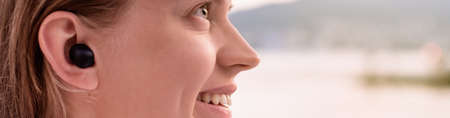 young woman closeup with wireless earphones on beach