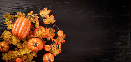 Halloween concept. Autumn decorations with pumpkins and leaves top view on black backgound with copy space. Bannerの写真素材