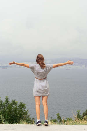 Back view of young woman in summer dress looking at the cityscape. Freedom concept. Travel concept