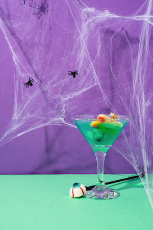 Scary colorful Halloween cocktails with party decorations on purple and green backgroundの写真素材