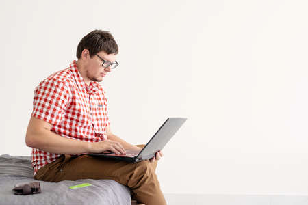 Online shopping concept. Young man sitting in the chair and shopping online using laptop looking at...