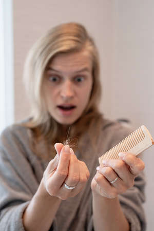 Womens health. Spa and wellness. Happy young woman applying hair mask in bathroomの写真素材