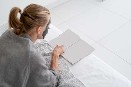 Leisure time. Young woman sitting at the chair at home reading a magazine