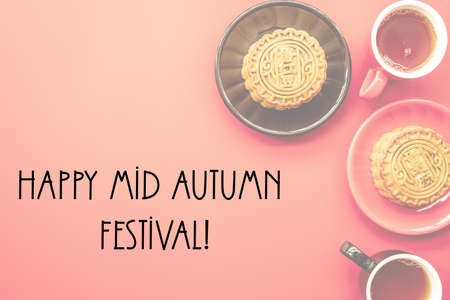 traditional chinese mid autumn festival food mooncakes on pink background with tea, spices and flowers flat lay, words Happy Mid Autumn Festivalの写真素材