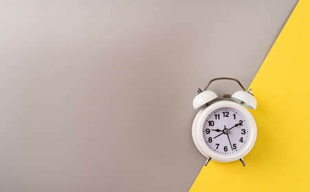 White retro alarm clock isolated on double yellow and gray background with copy spaceの写真素材