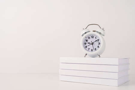 White alarm clock on stack of books, mockup designの写真素材