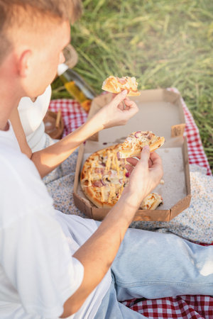 Autumn nature. Fun and liesure. Young teenage couple picnic on sunflower field in sunset drinking champagne toastingの写真素材