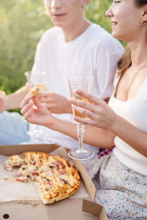 Autumn nature. Fun and liesure. Young teenage couple picnic on sunflower field in sunset drinking champagne toastingの写真素材