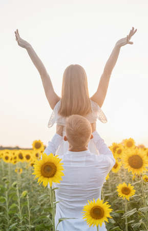 Autumn nature. Young romantic couple walking in sunflower field in sunsetの写真素材
