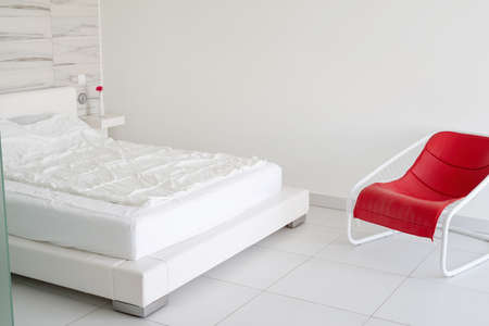 Interior design. modern light and airy bedroom with bed and red chairの写真素材