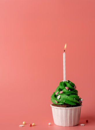 Merry christmas and happy new year. Green Christmas tree shaped cupcake with a candle on pink background. Minimal style, copy spaceの写真素材