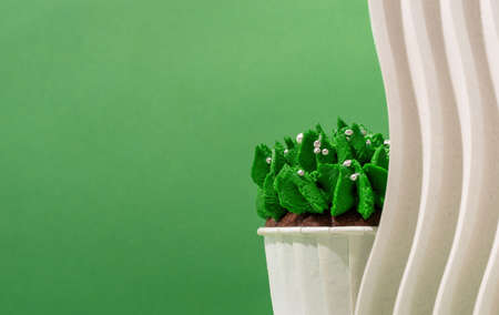 Merry christmas and happy new year. Composition of green Christmas tree shaped cupcakes on white poduims, abstract and modern minimal style, green solid background, copy spaceの写真素材