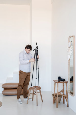 Minimal light and airy interior design. Male photographer working in minimal light and airy interior, white and beige chair, rug and pillowsの写真素材
