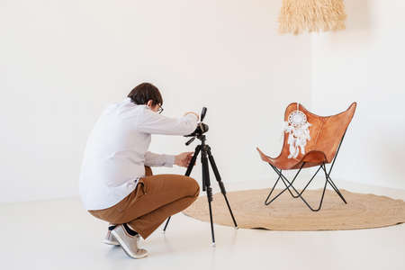 Minimal light and airy interior design. Male photographer working in minimal light and airy interior, white and beige chair, rug and pillowsの写真素材