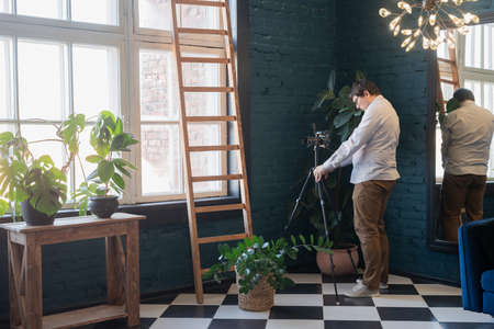 Young woman in green sweater taking care of the plants at homeの写真素材