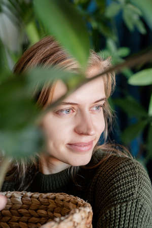 Female photographer in green sweater taking selfie using camera looking at the mirrorの写真素材