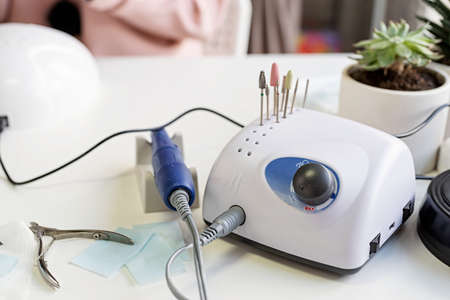 Manicure and pedicure salon, social distance. Nail drill or manicure machine on the table in nail...