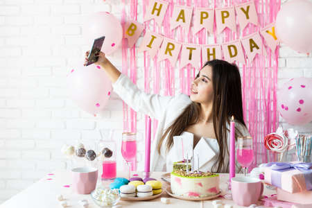 birthday party. birthday tables. Attractive woman in white party clothes celebrating birthday taking...