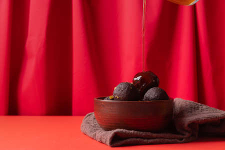 Traditional Indian sweets. Sweet Gulab Jamun with syrup on red background