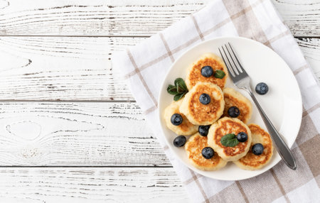 Cottage cheese fritters with blueberries on ceramic plate on wooden background. Healthy calcium breakfast, lunch or snack. traditional russian food. close upの写真素材