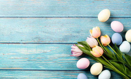 Home decoration for holiday. easter background with eggs and tulips on blue wooden backdrop, top...