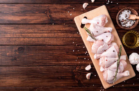 Sliced chicken legs with skin on a cutting board. Dark wooden background. top viewの写真素材