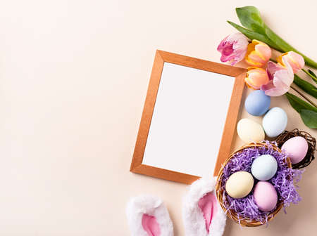 Wooden frame with easter decorations flat lay on beige backgroundの写真素材