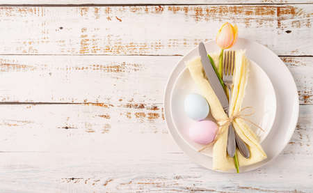 Happy Easter. Table setting for Easter feast. Easter eggs, tulips and cutlery top view flat lay on...