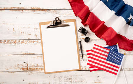 Blank paper on craft clipboard for mockup design with USA flag and ink top view flat layの写真素材