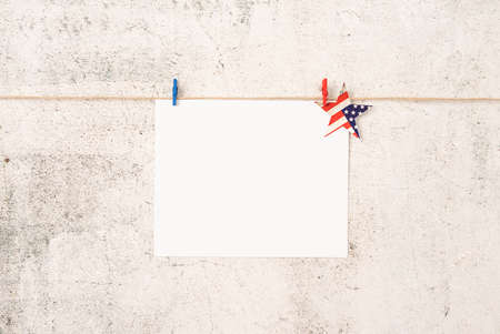 USA Memorial day, Presidents day, Veterans day, Labor day, or 4th of July celebration. Blank white paper for mockup design with red and blue clips on craft ropeの写真素材