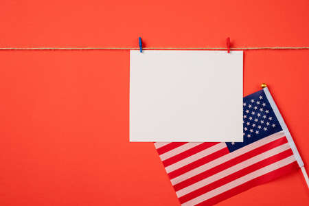 USA Memorial day, Presidents day, Veterans day, Labor day, or 4th of July celebration. Blank white paper for mockup design with red and blue clips on craft rope, red backgroundの写真素材