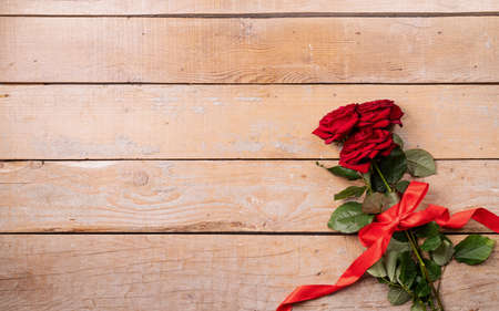 Romantic Valentine's day flat lay with copy space for text. Red roses bouquet with copy space top view on wooden background. valentine's day greeting cardの写真素材