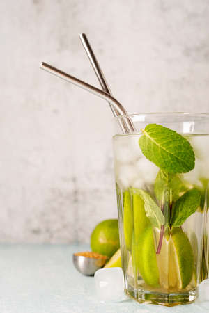 fresh summer caipirinha cocktail on concrete background with green fruit lime on table