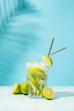 fresh summer caipirinha cocktail on blue background with green fruit lime on tableの写真素材