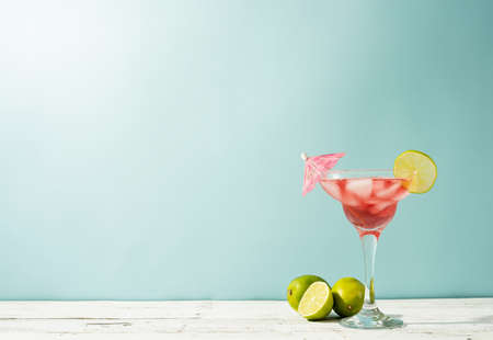 Fresh strawberry alcohol cocktail. Fresh summer cocktail with strawberry, lime and ice cubes on blue background with copy spaceの写真素材