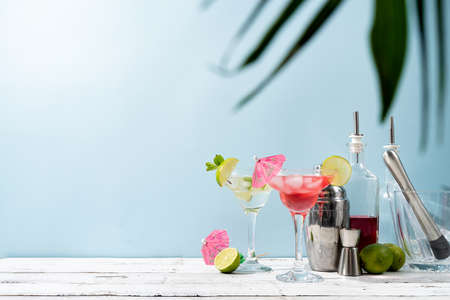 Fresh strawberry alcohol cocktails. Fresh summer cocktails and bar equipment with strawberry, lime and ice cubes on blue background with copy spaceの写真素材